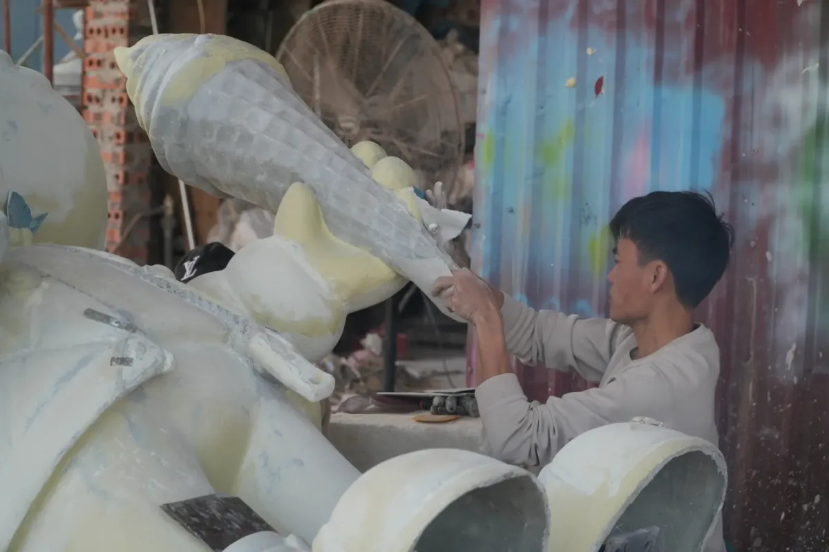 Người thợ thao tác trên mặt ngoài của phần tạo hình thuôn dài nhô lên trong xưởng