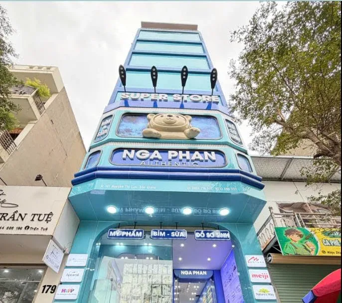 Mô hình nhân vật màu kem đặt phía trên dòng chữ NGA PHAN trên mặt tiền cửa hàng.