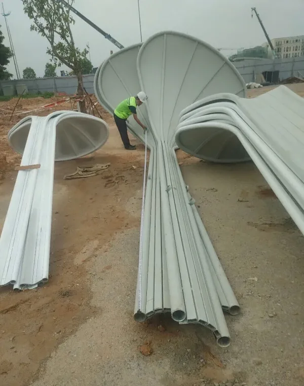 Công nhân đo các cấu kiện tạo hình cánh hoa phượng tại khu vực tập kết ngoài trời