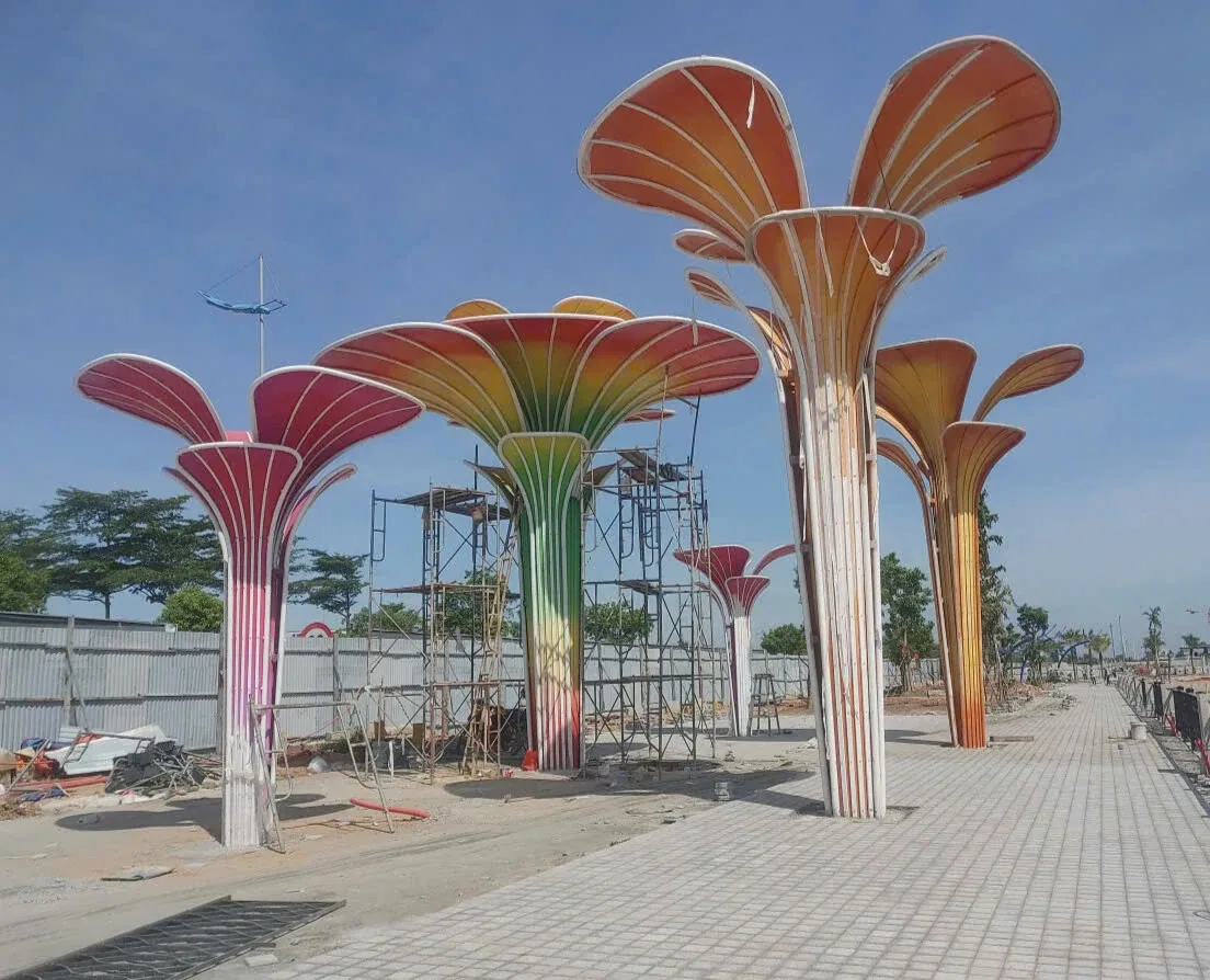 Các cụm trụ hoa cách điệu nhiều màu đang được lắp đặt dọc lối đi ngoài trời trong khu đô thị.