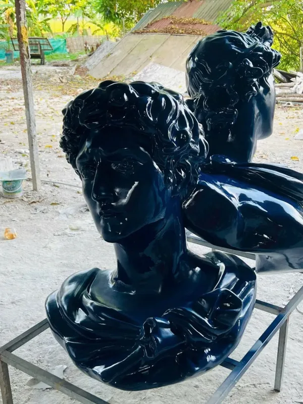 Các tượng bán thân nghệ thuật màu đen bóng đặt trên khung sắt tại xưởng
