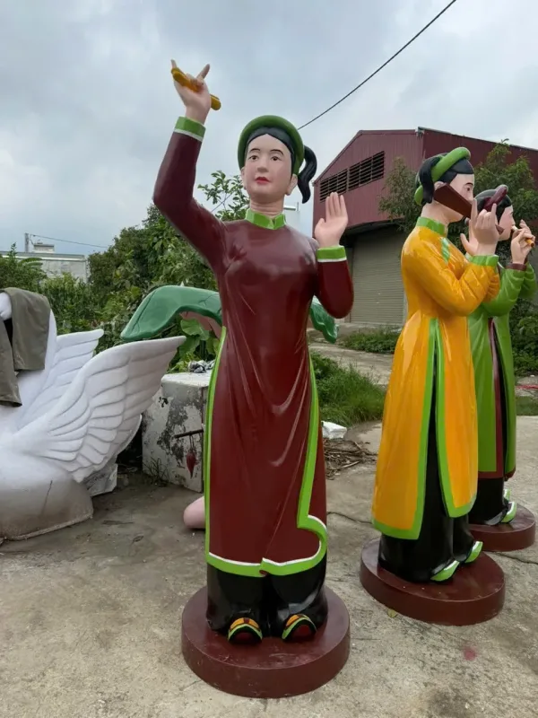 Cụm tượng phụ nữ mặc áo dài, tạo dáng biểu diễn với đạo cụ trên tay