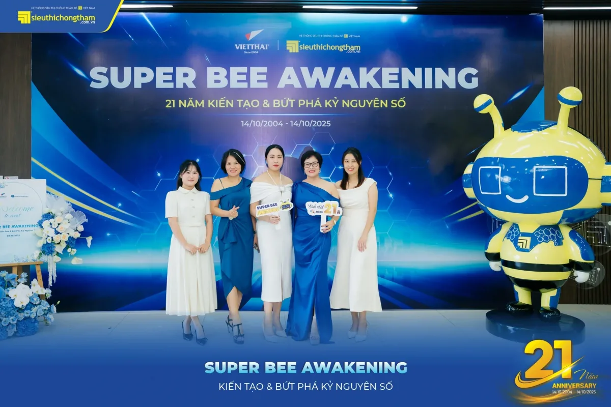 Năm khách mời đứng chụp ảnh trước backdrop Super Bee Awakening, bên cạnh là linh vật ong vàng xanh cỡ lớn và logo sự kiện...
