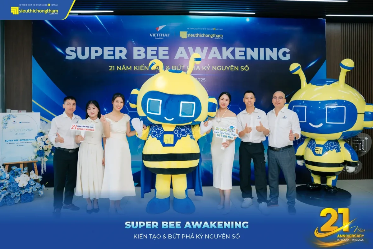 Nhóm khách đứng chụp ảnh cùng hai linh vật ong vàng xanh trước phông nền sự kiện Super Bee Awakening của Siêu Thị Chống Thấm.