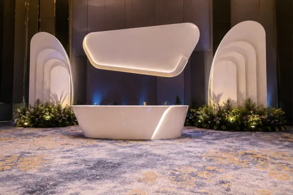 bản dựng khu check-in gần sân khấu có khoảng đứng cho khách, logo composite ở phía trên và khối xốp trang trí hai bên để...