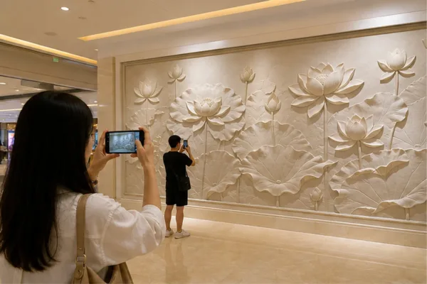 Khách chụp ảnh trước vách phù điêu hoa sen trong trung tâm thương mại